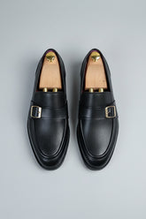 Black leather dress shoes with buckle detail, ideal for formal wear and business occasions.